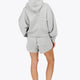 Woman wearing the Osaka women hoodie in heather grey with white logo. Back view
