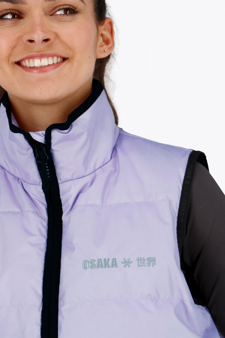 Woman wearing the Osaka women padded gilet in purple with grey logo. Front detail logo view