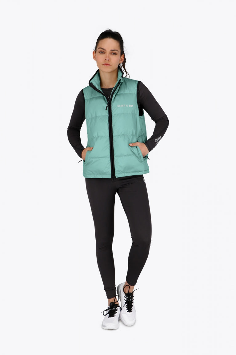 Woman wearing the Osaka women padded gilet in green with grey logo. Front view