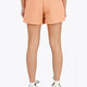 Woman wearing the Osaka women shorts in peach with logo in white. Back view