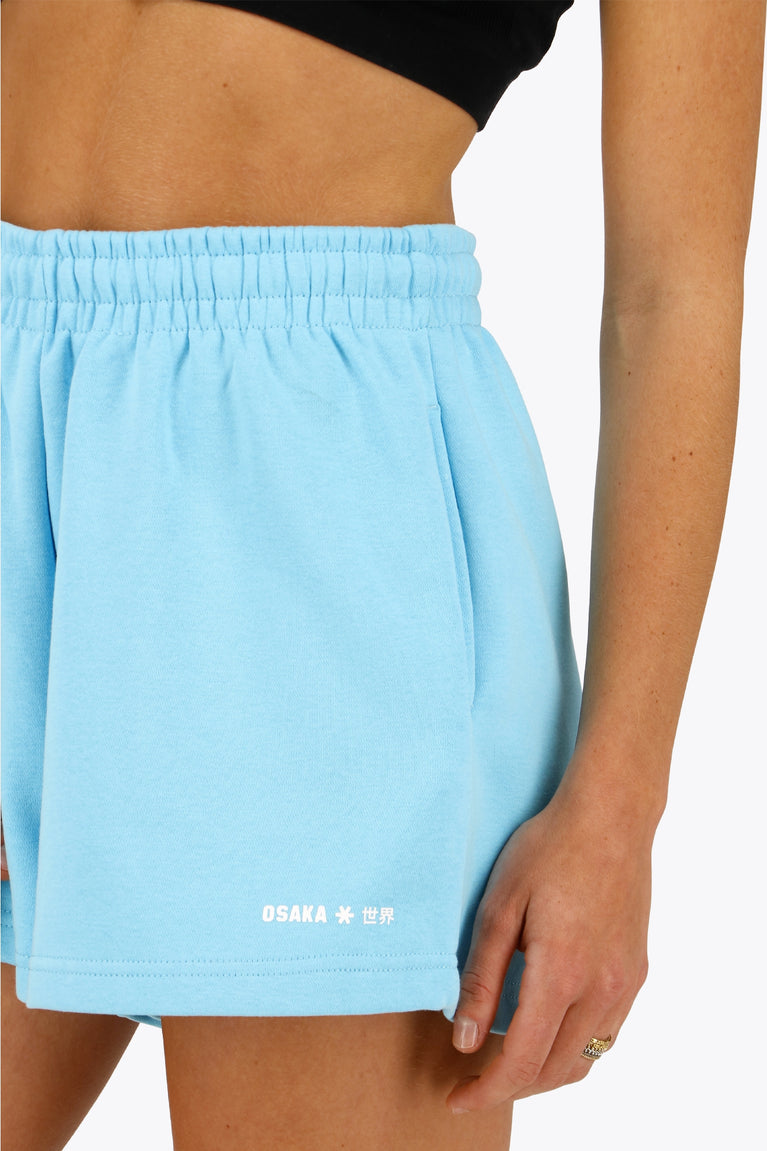 Woman wearing the Osaka women shorts in light blue with logo in white. Front detail logo view