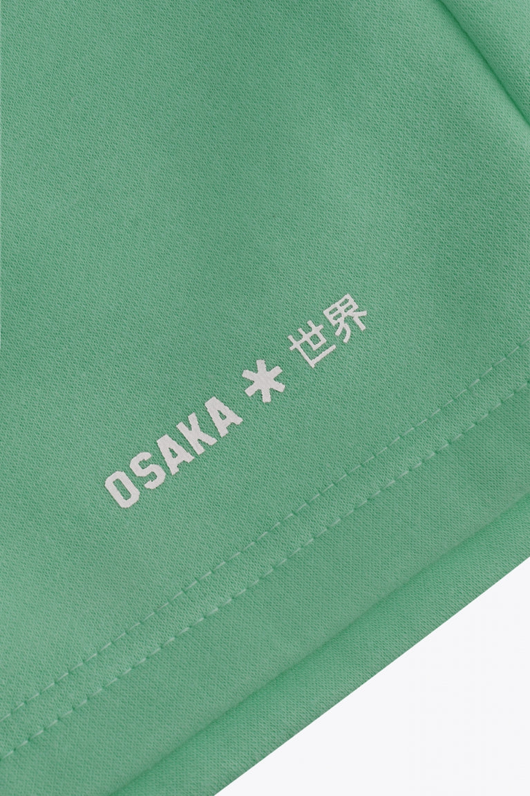 Osaka women shorts in green with logo in white. Front flatlay detail logo view