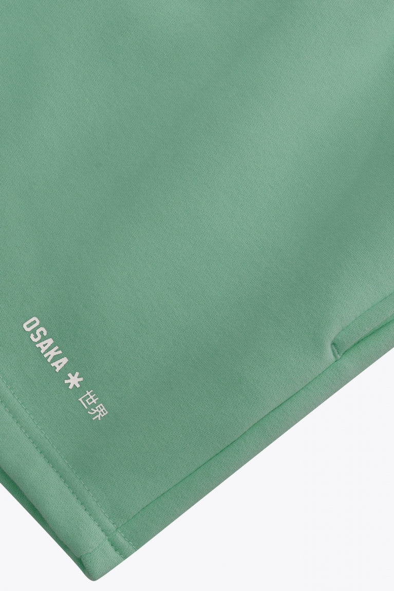 Osaka women shorts in green with logo in white. Front flatlay detail logo view