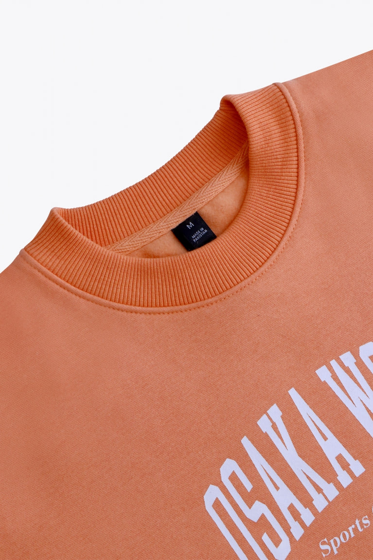 Osaka women sweater in peach with logo in white. Front flatlay neck view
