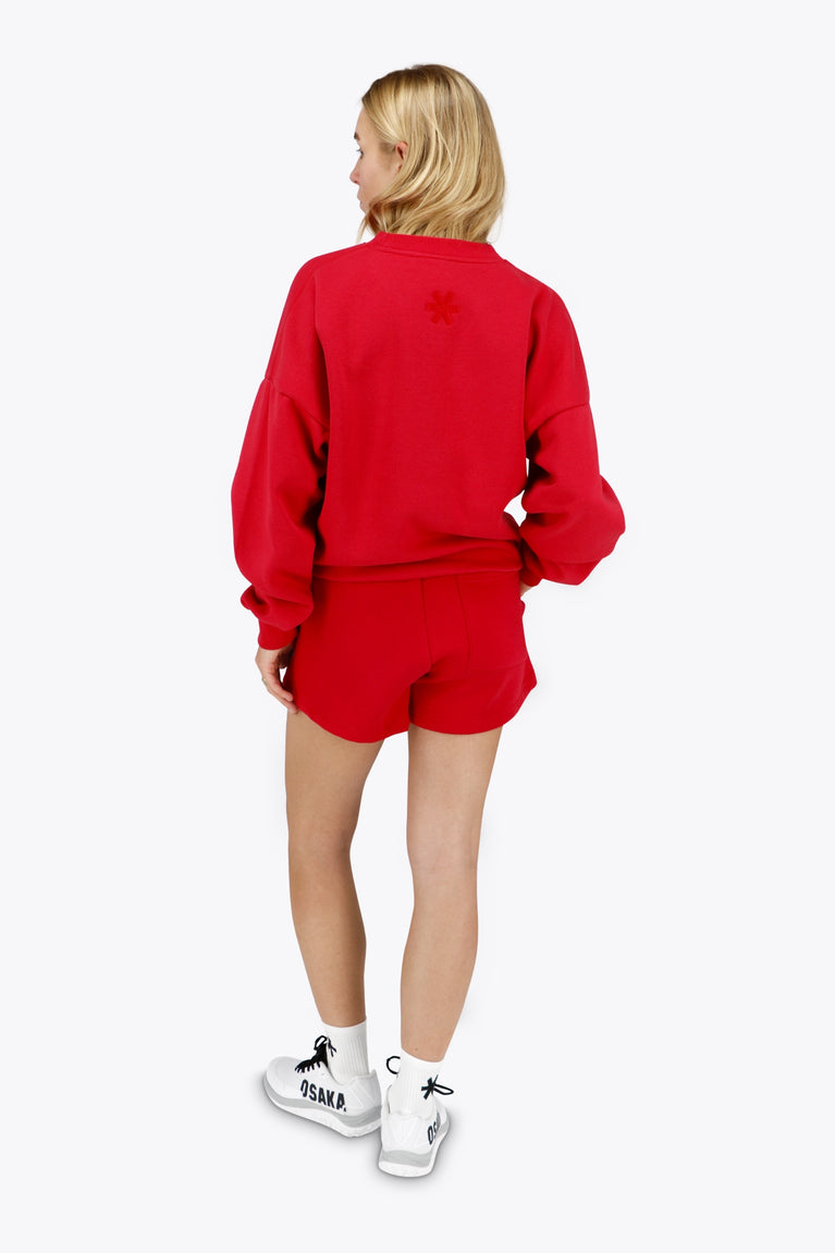 Woman wearing the Osaka women sweater in red with logo in white. Back view