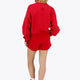 Woman wearing the Osaka women sweater in red with logo in white. Back view