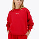 Woman wearing the Osaka women sweater in red with logo in white. Front view