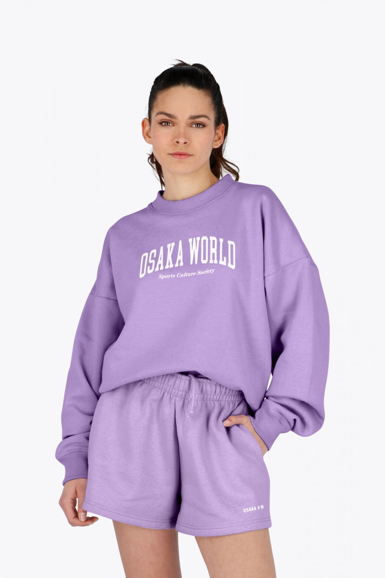 Woman wearing the Osaka women sweater in light purple with logo in white. Front view
