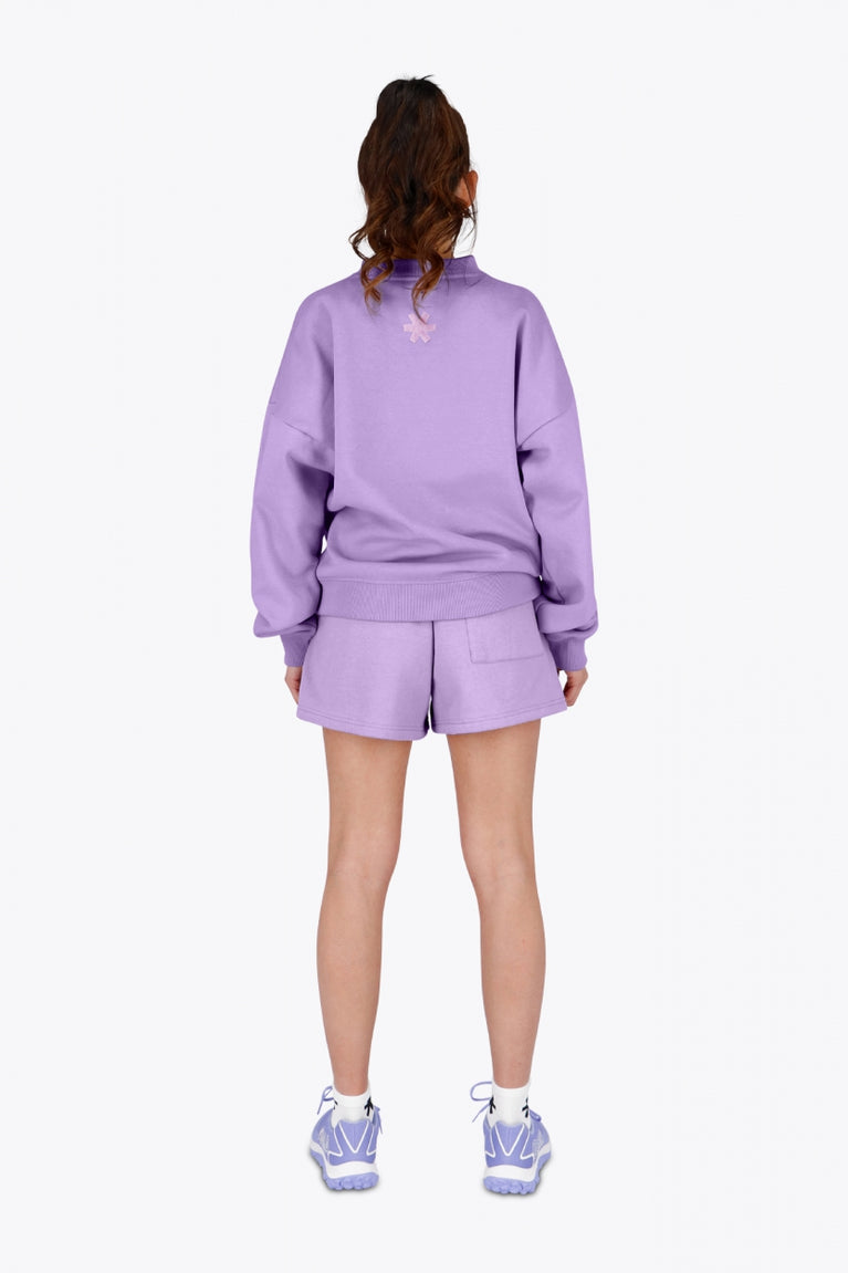 Woman wearing the Osaka women sweater in light purple with logo in white. Back view