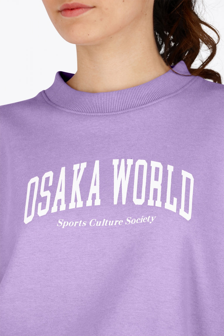 Woman wearing the Osaka women sweater in light purple with logo in white. Front detail logo view