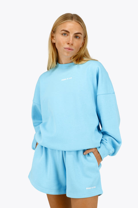 Osaka women sweater in light blue with logo in white. Front flatlay view