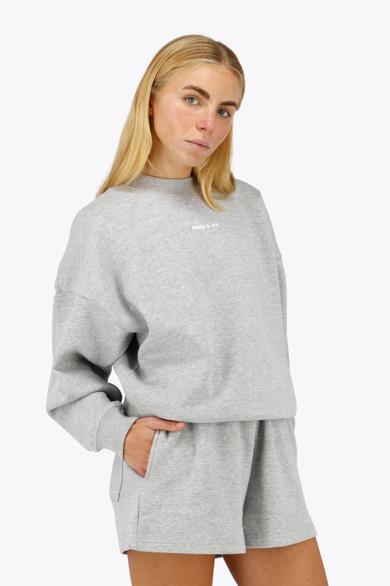 Woman wearing the Osaka women sweater in heather grey with logo in white. Front view