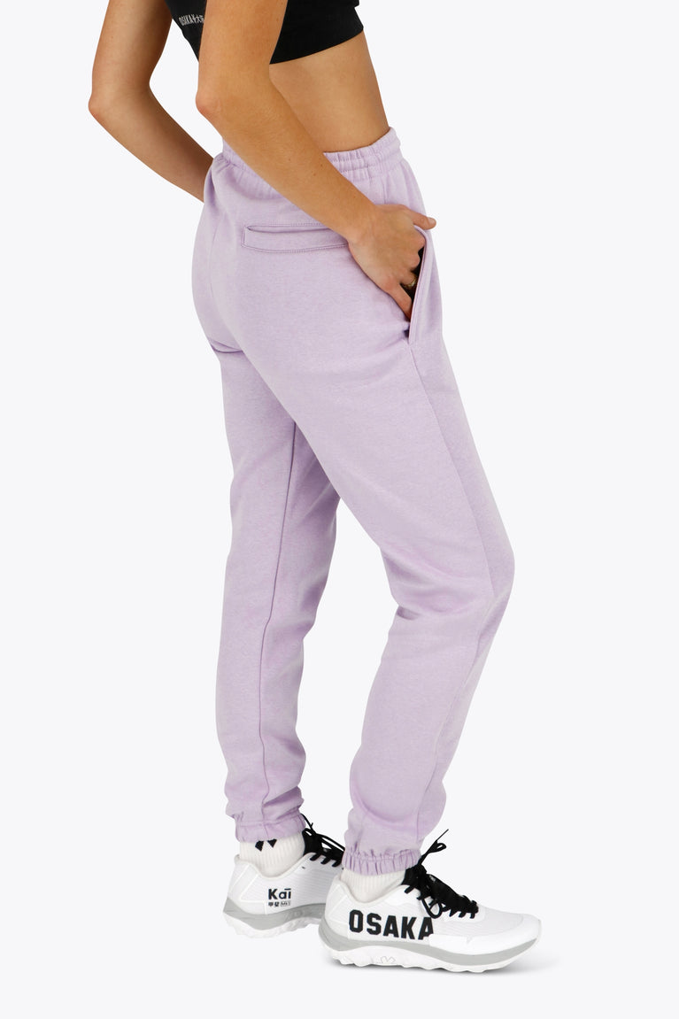 Woman wearing the Osaka women sweatpants in light purple with logo in white. Side / back view