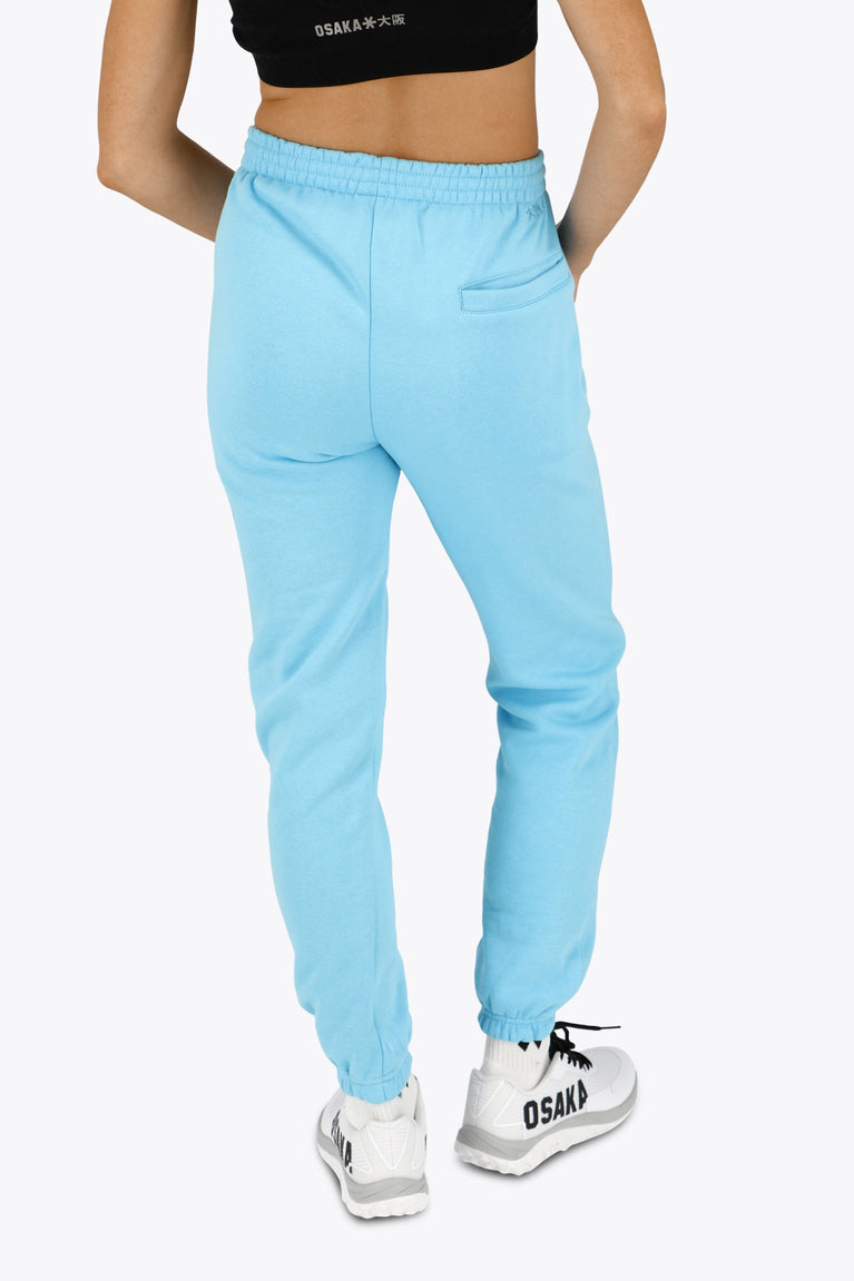 Woman wearing the Osaka women sweatpants in light blue with logo in white. Back view