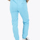 Woman wearing the Osaka women sweatpants in light blue with logo in white. Back view