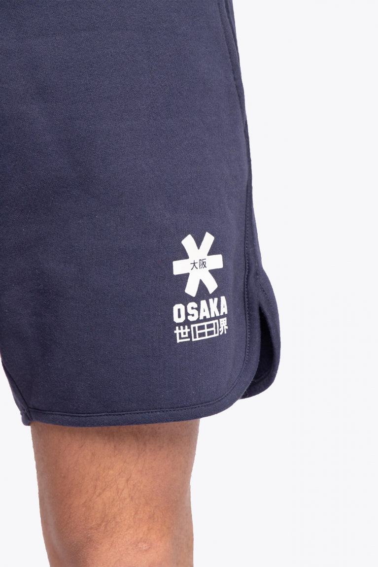 Man wearing the Osaka court classic short in navy with white logo. Detail logo view
