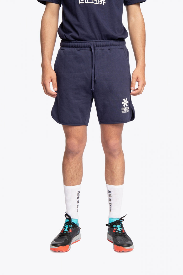 Man wearing the Osaka court classic short in navy with white logo. Front view