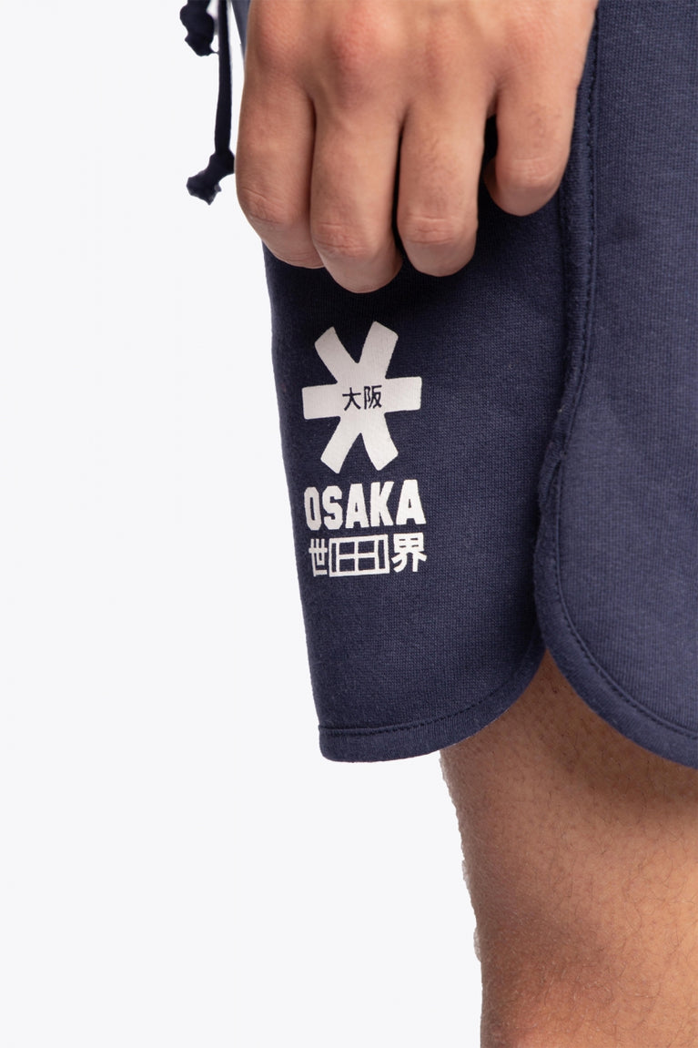 Man wearing the Osaka court classic short in navy with white logo. Detail logo view