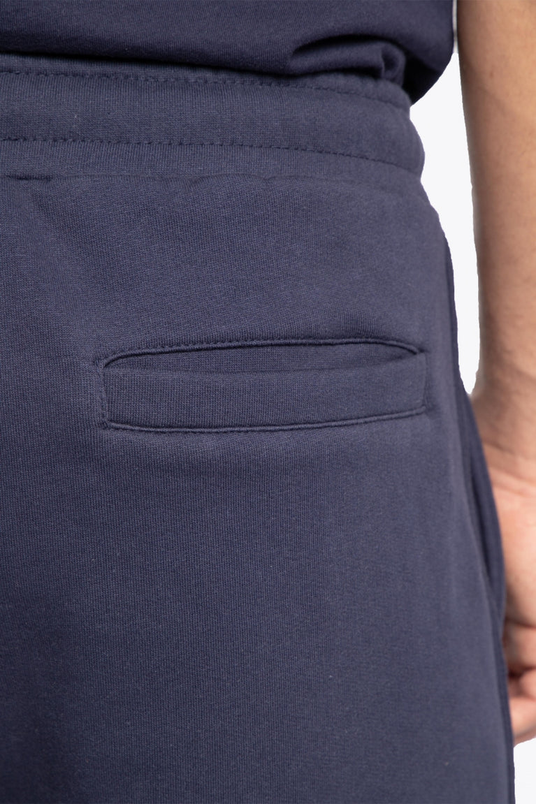 Man wearing the Osaka court classic short in navy with white logo. Detail pocket view