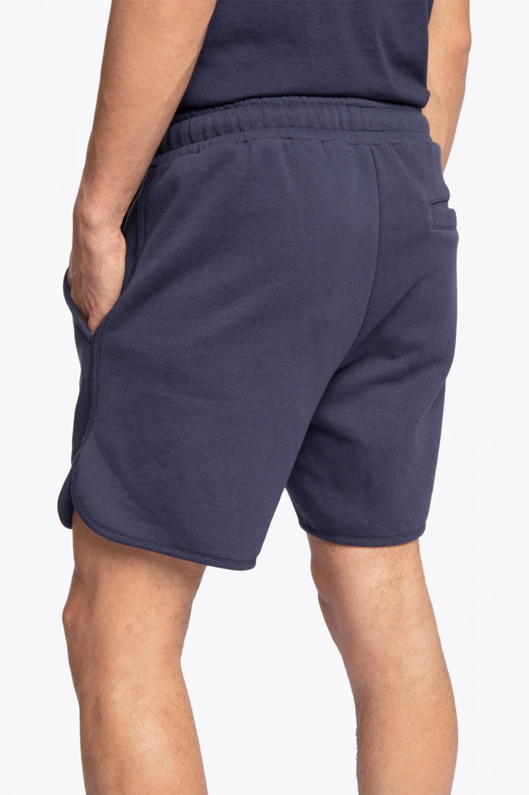 Man wearing the Osaka court classic short in navy with white logo. Side / back view