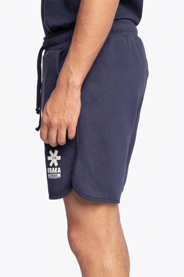 Man wearing the Osaka court classic short in navy with white logo. Side view