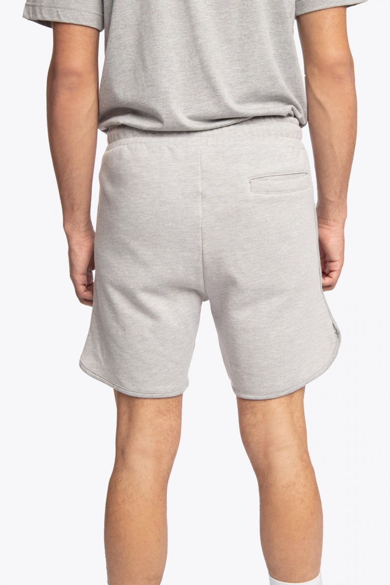 Man wearing the Osaka Men padel shorts in grey with green logo on it. Back view