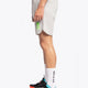 Man wearing the Osaka Men padel shorts in grey with green logo on it. Side view