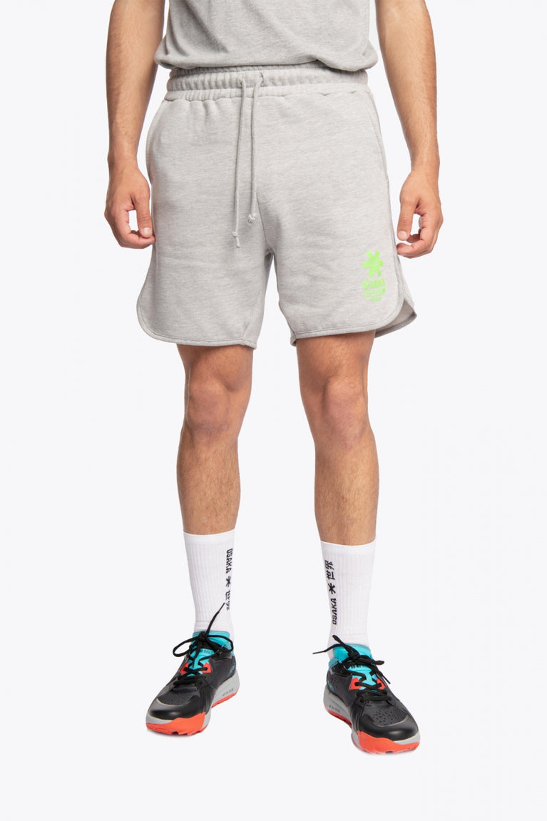 Man wearing the Osaka Men padel shorts in grey with green logo on it. Front view