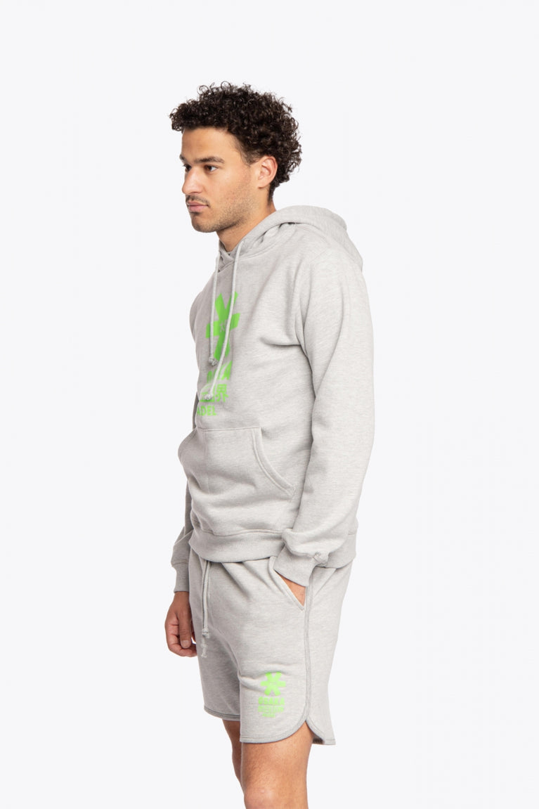 Man wearing the Osaka basic unisex hoodie in grey with green logo on it. Side / front view