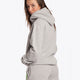 Woman wearing the Osaka basic unisex hoodie in grey with green logo on it. Back view