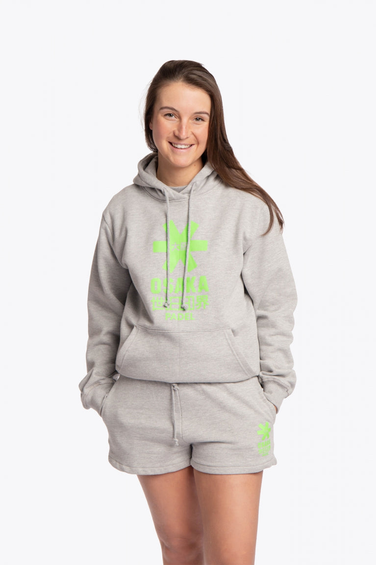 Woman wearing the Osaka basic unisex hoodie in grey with green logo on it. Front view