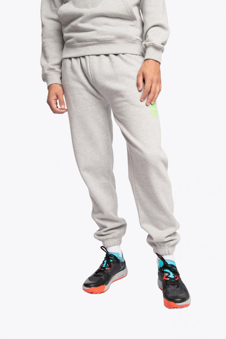 Man wearing the Osaka unisex sweatpants in heather grey with logo in green. Front view