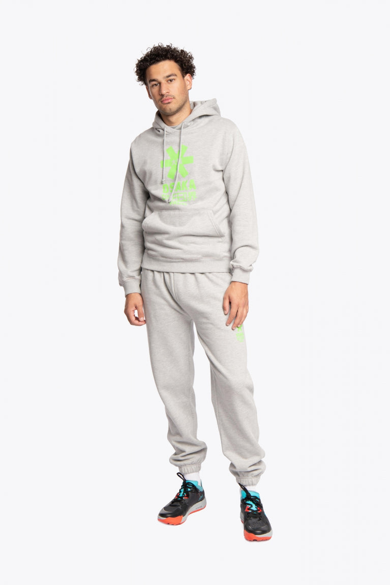 Man wearing the Osaka unisex sweatpants in heather grey with logo in green. Front view