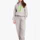 Woman wearing the Osaka unisex sweatpants in heather grey with logo in green. Front view