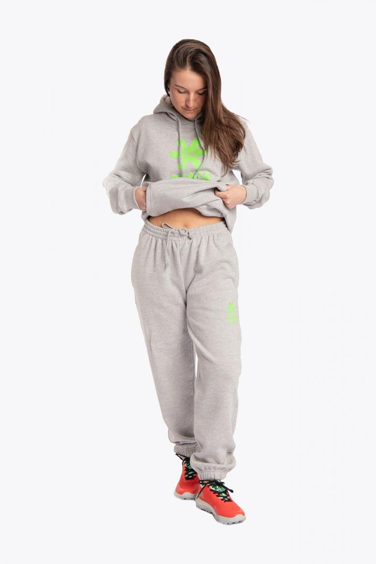 Woman wearing the Osaka unisex sweatpants in heather grey with logo in green. Front view