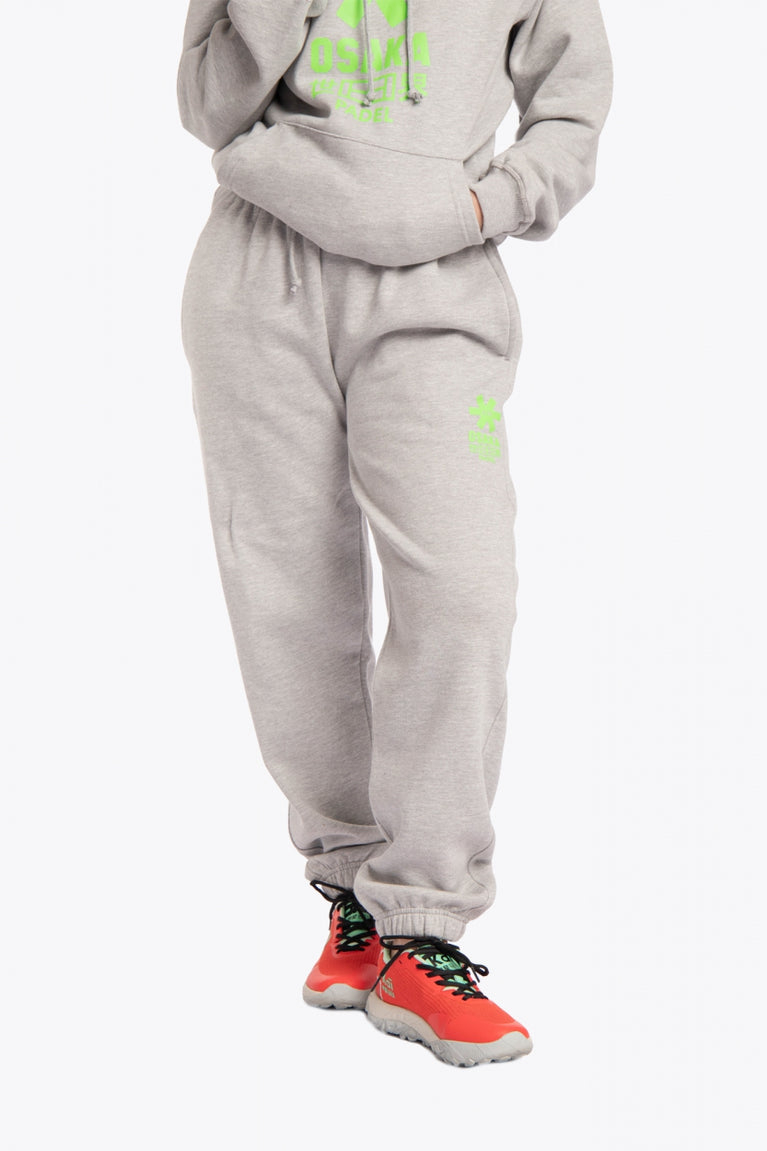 Model wearing the Osaka unisex sweatpants in heather grey with logo in green. Front view