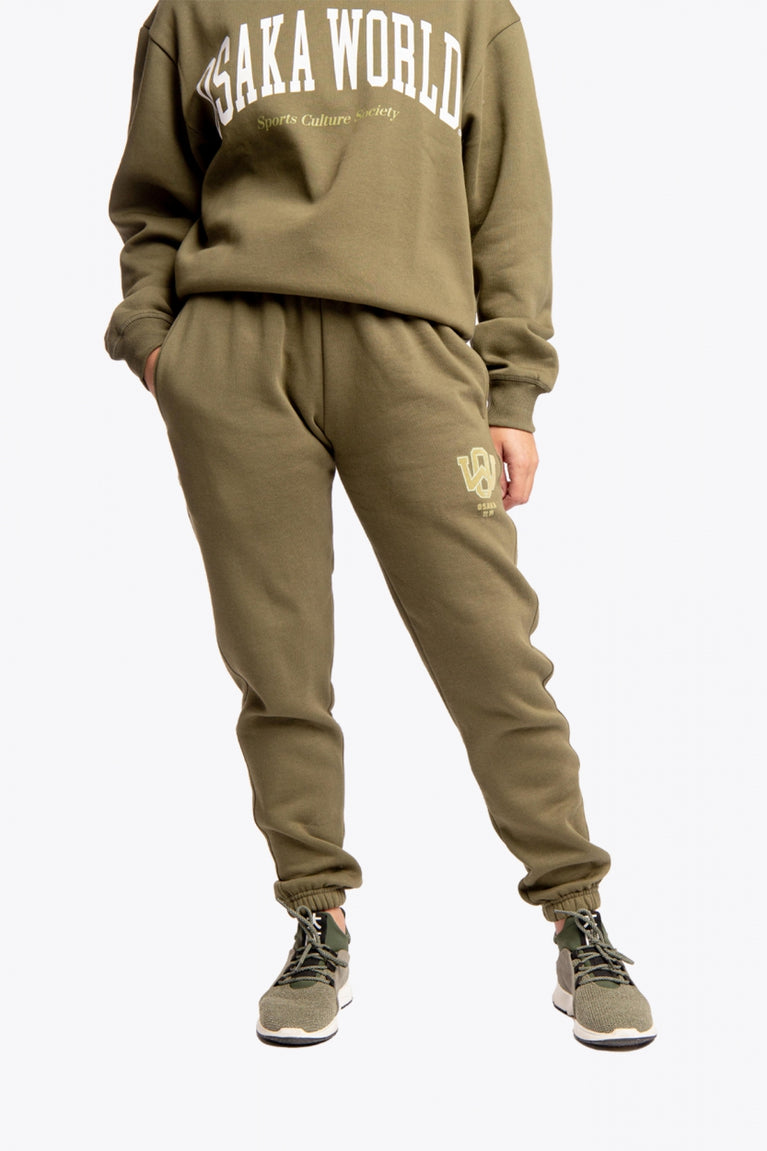 Model wearing the Osaka unisex sweatpants in army green with logo in yellow. Front view