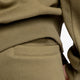 Model wearing the Osaka unisex sweatpants in army green with logo in yellow. Detail back pocket view