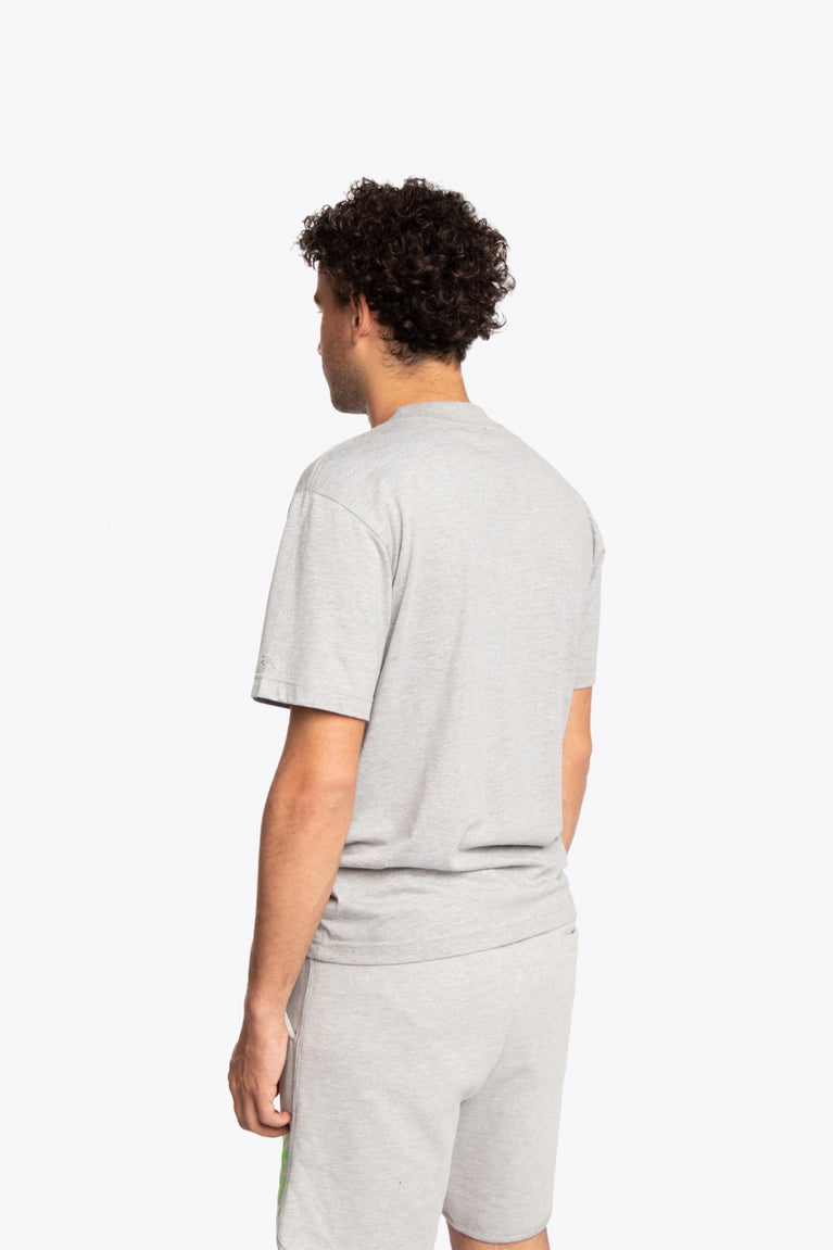 Man wearing the Osaka unisex tee in heather grey with green logo. Back side view