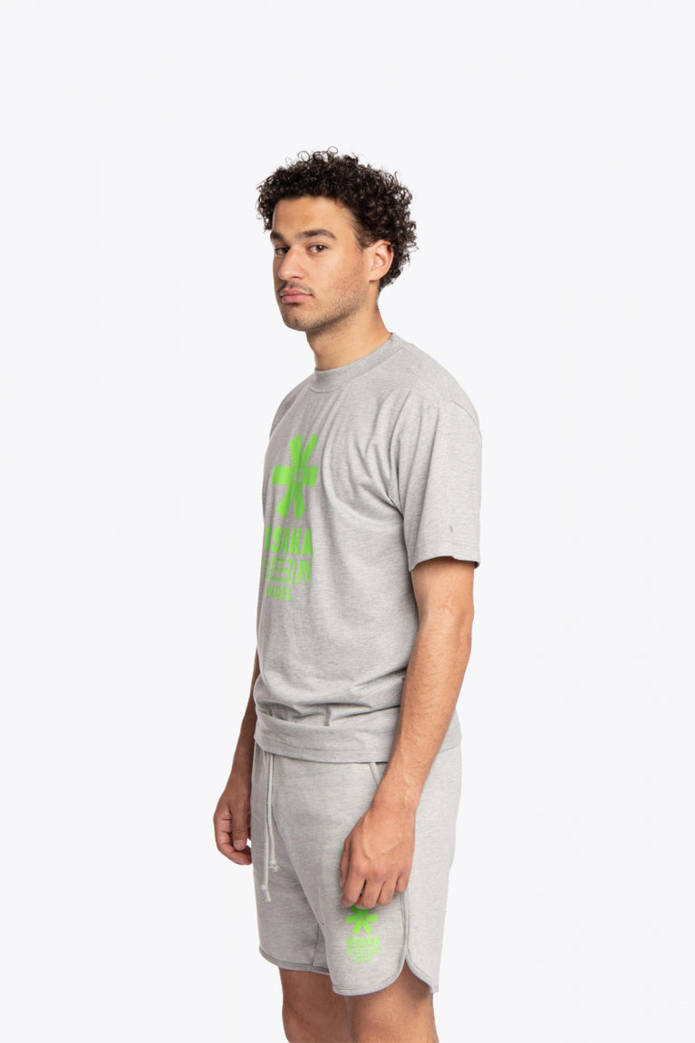 Man wearing the Osaka unisex tee in heather grey with green logo. Side front view