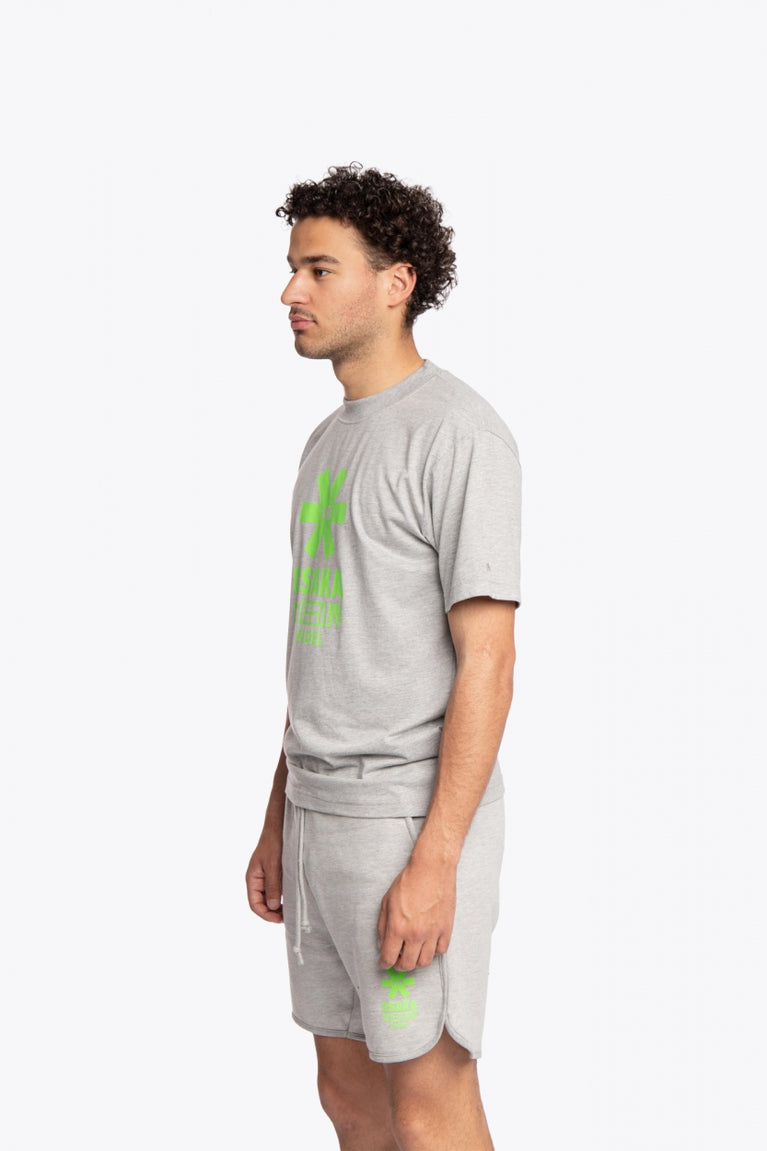 Man wearing the Osaka unisex tee in heather grey with green logo. Side view