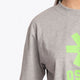 Woman wearing the Osaka unisex tee in heather grey with green logo. Detail sleeve view