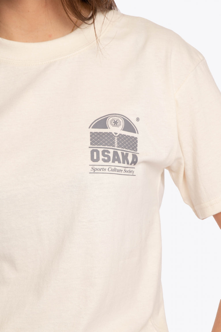 Woman wearing the Osaka unisex tee in cream with logo in grey. Detail logo view