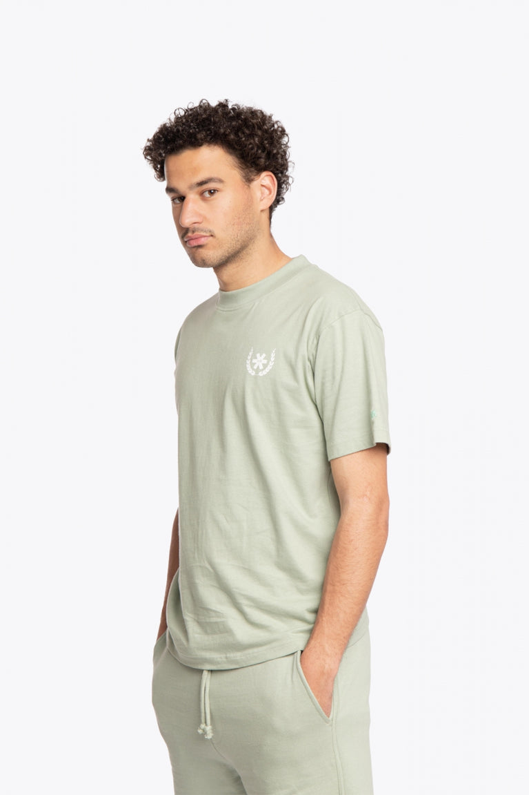 Man wearing the Osaka unisex tee in iceberg green with white logo. Side front view