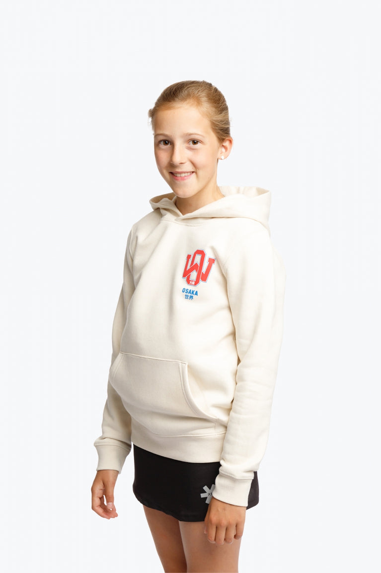 Girl wearing the Osaka kids hoodie in natural raw with college letters in orange and logo in blue. Front/side view