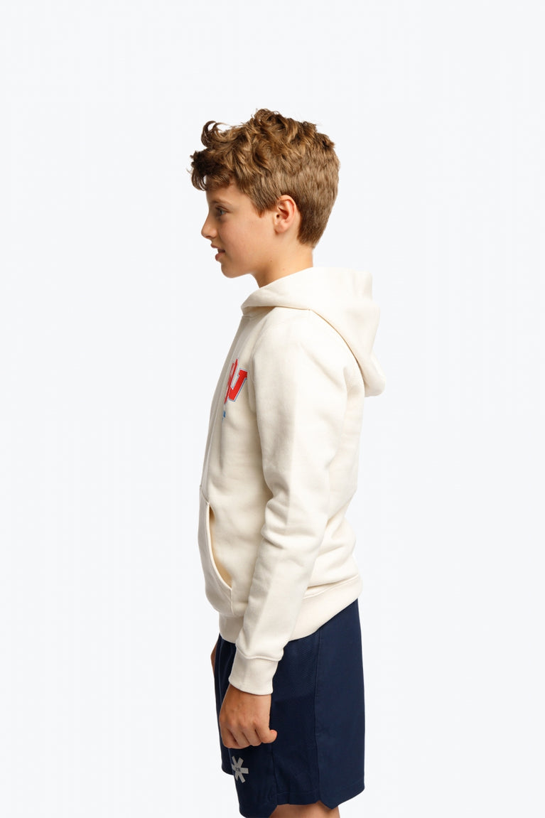 Boy wearing the Osaka kids hoodie in natural raw with college letters in orange and logo in blue. Side view