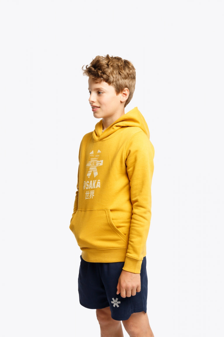 Boy wearing the Osaka kids hoodie in ochre and marker logo in white. Front/side view