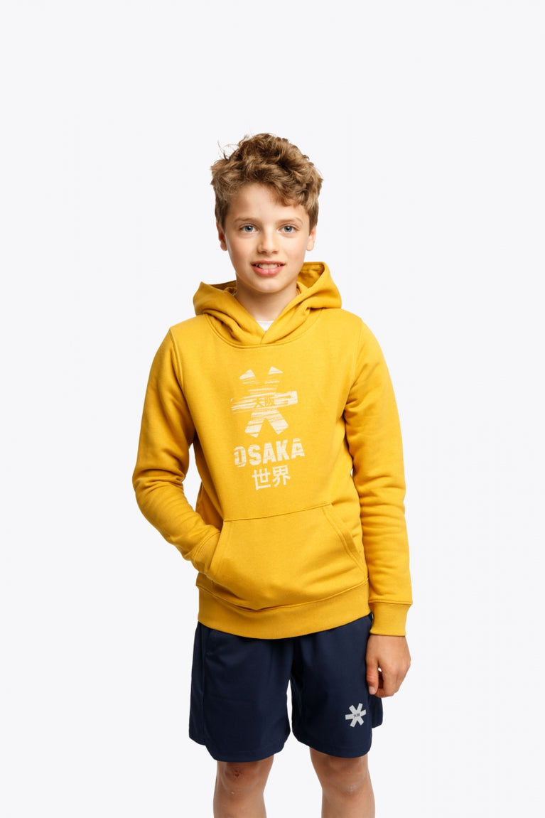 Boy wearing the Osaka kids hoodie in ochre and marker logo in white. Front view