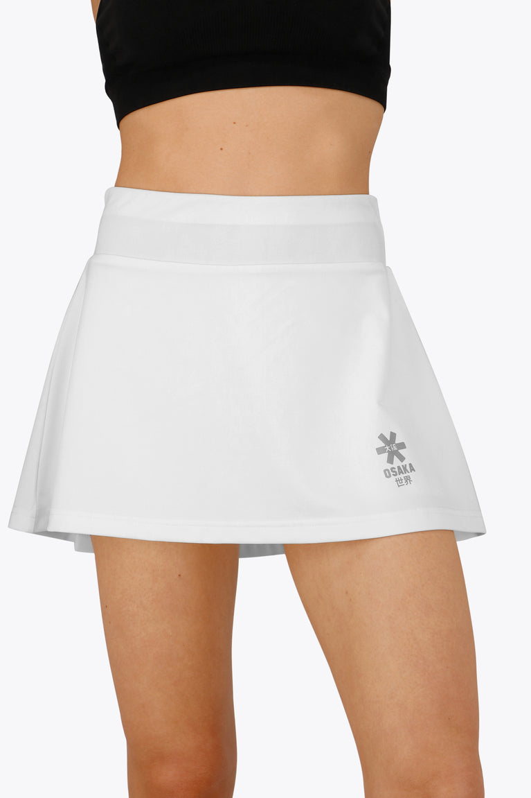 Woman wearing the Osaka women floucy skort white with logo in grey. Front view