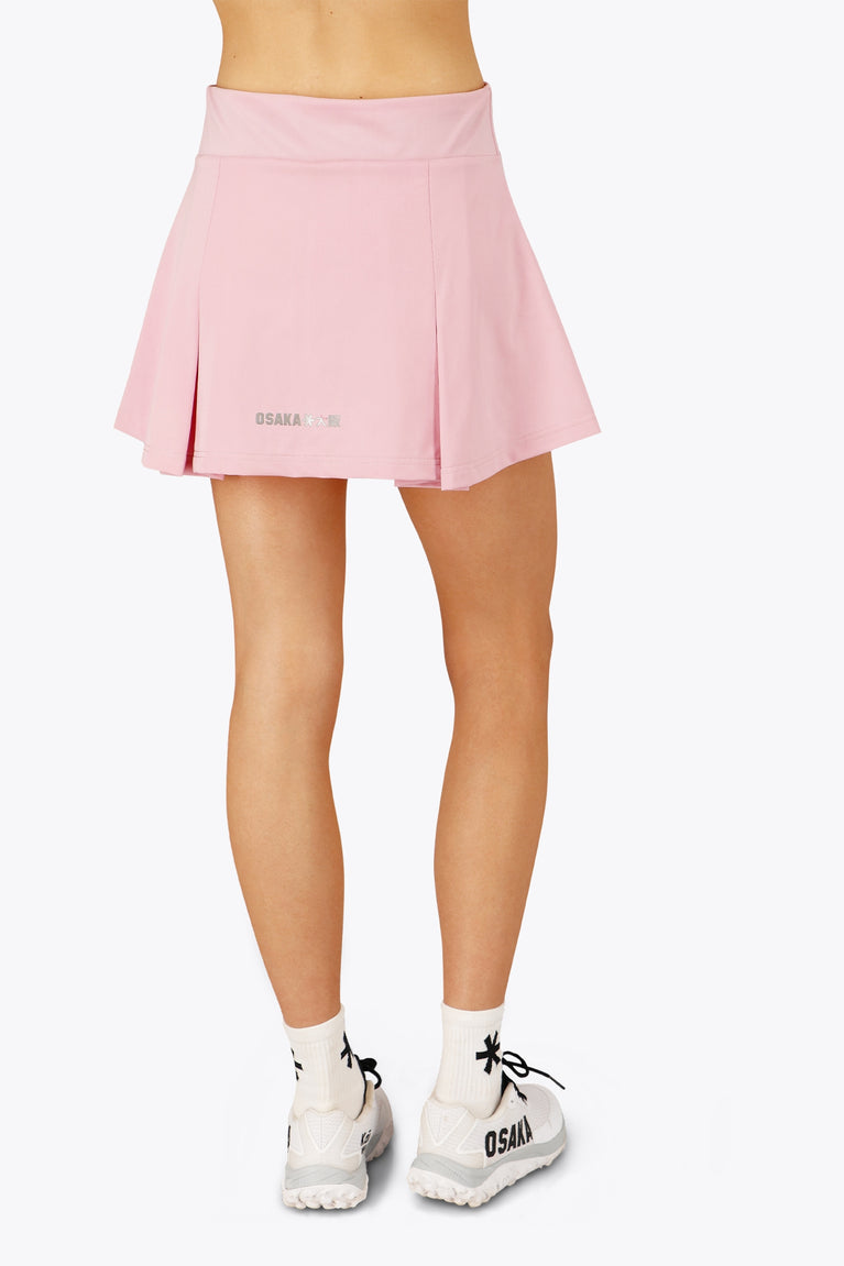 Woman wearing the Osaka women floucy skort pink with logo in grey. Back view